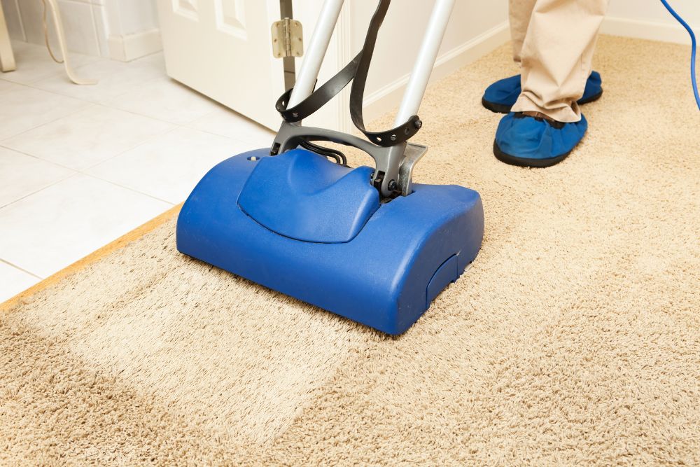A person cleans a carpet with a vacuum cleaner, representing a cleaning service in Austin, TX.
