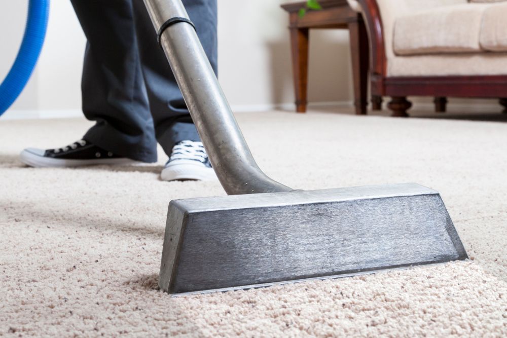 A person operates a vacuum cleaner on a carpet, showcasing a carpet restoration service in Austin, TX.