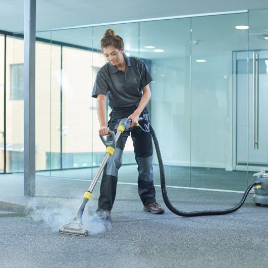 A woman operates a vacuum cleaner on a carpet, illustrating a carpet and rug cleaning service in Austin, TX.