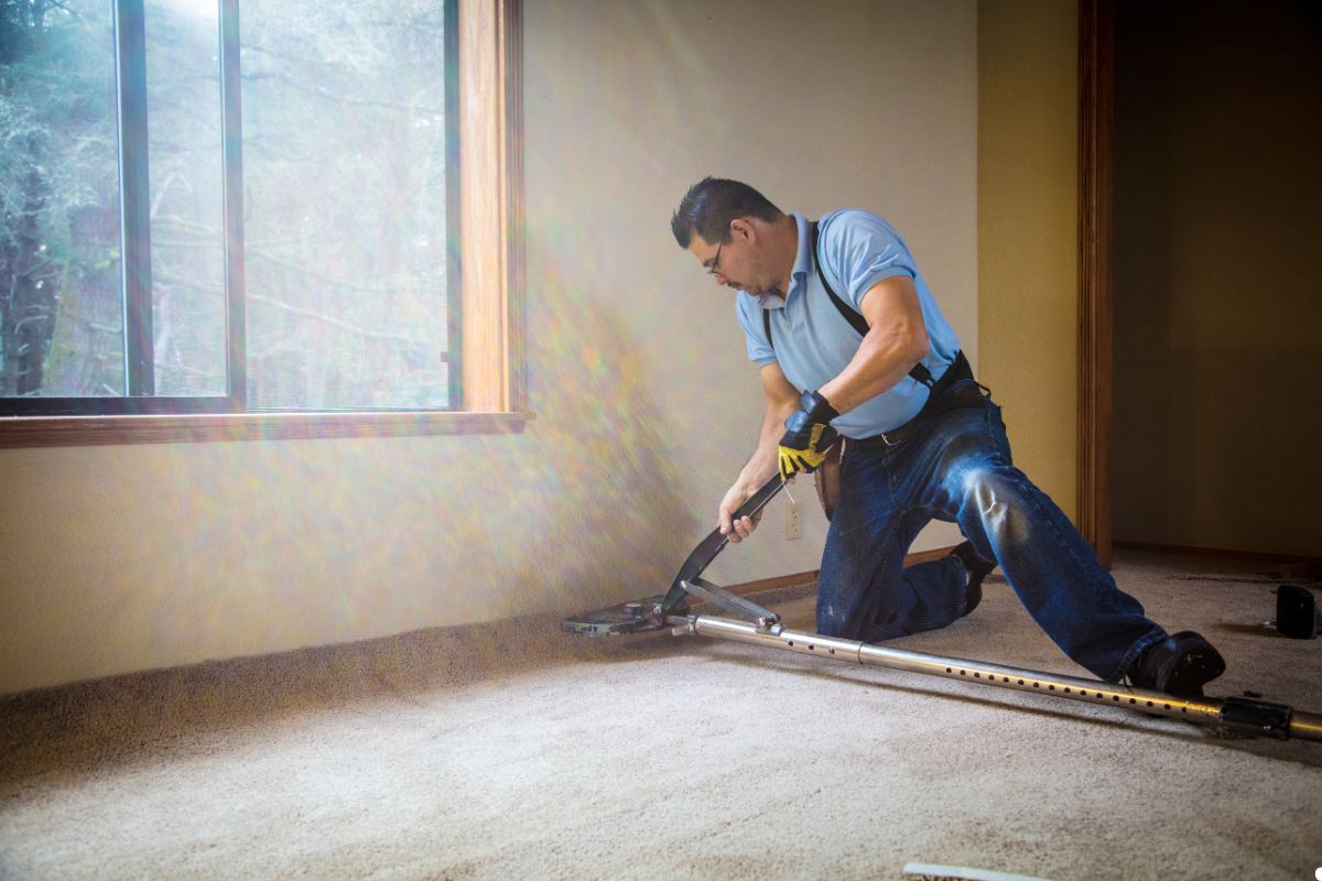  A man operates a vacuum cleaner on a carpet, effectively removing dirt and debris from the surface.